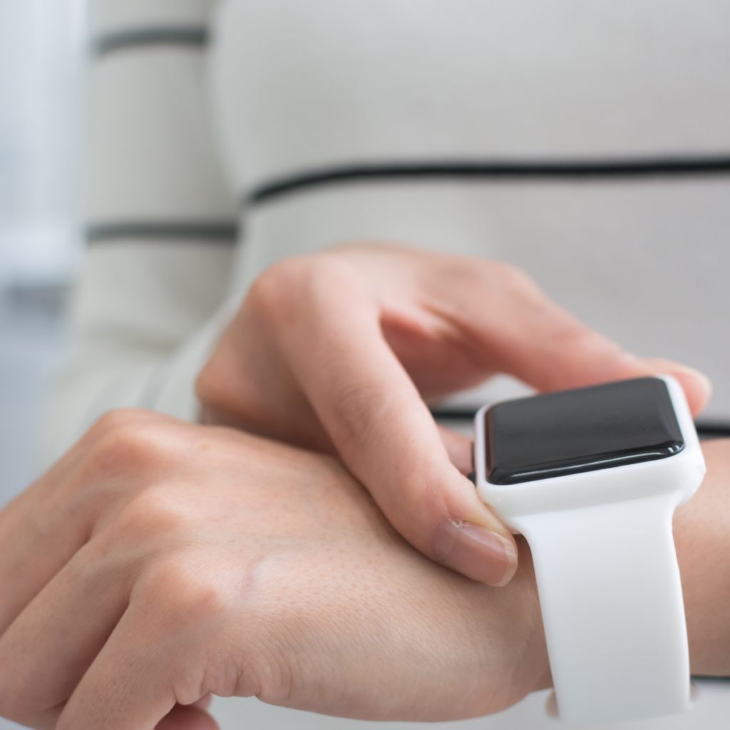 A person touching the screen of a white smartwatch on their wrist